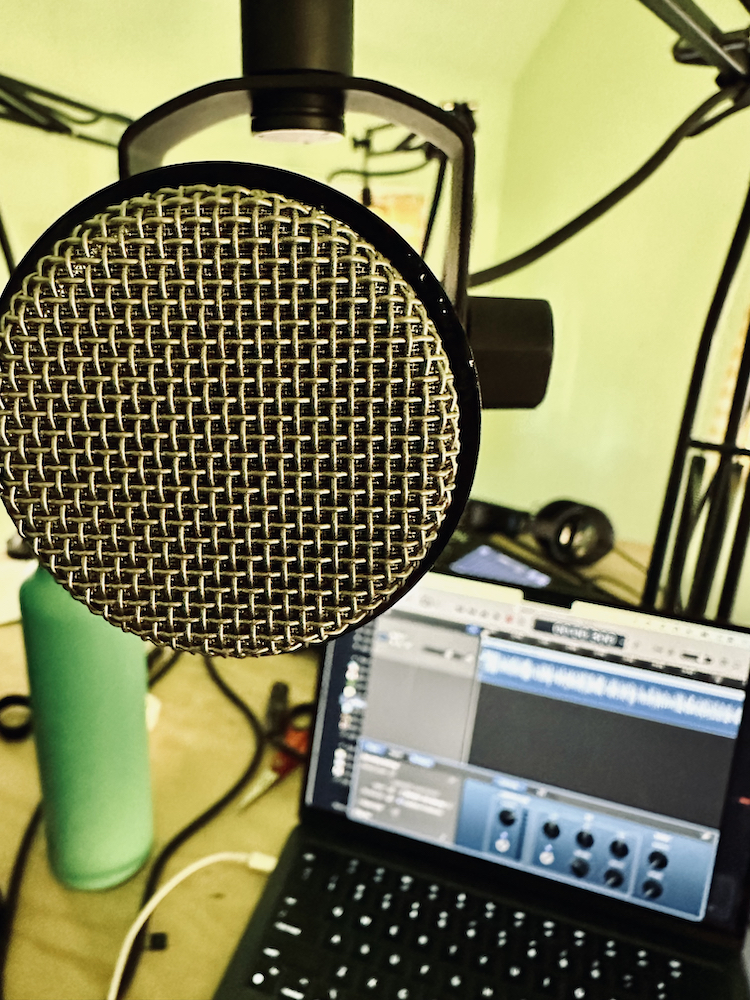 closeup of a microphone with a blurry MacBook Air in the background using GarageBand